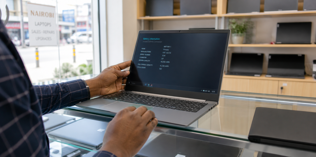 Used laptop buyer checking battery, screen and keyboard in a Nairobi electronics shop